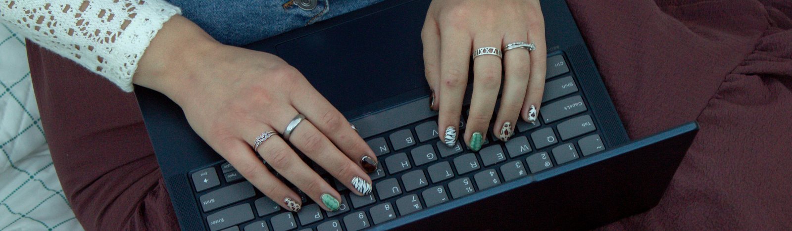 Lynea Millward's hands at a laptop keyboard, quilt and skirt around it