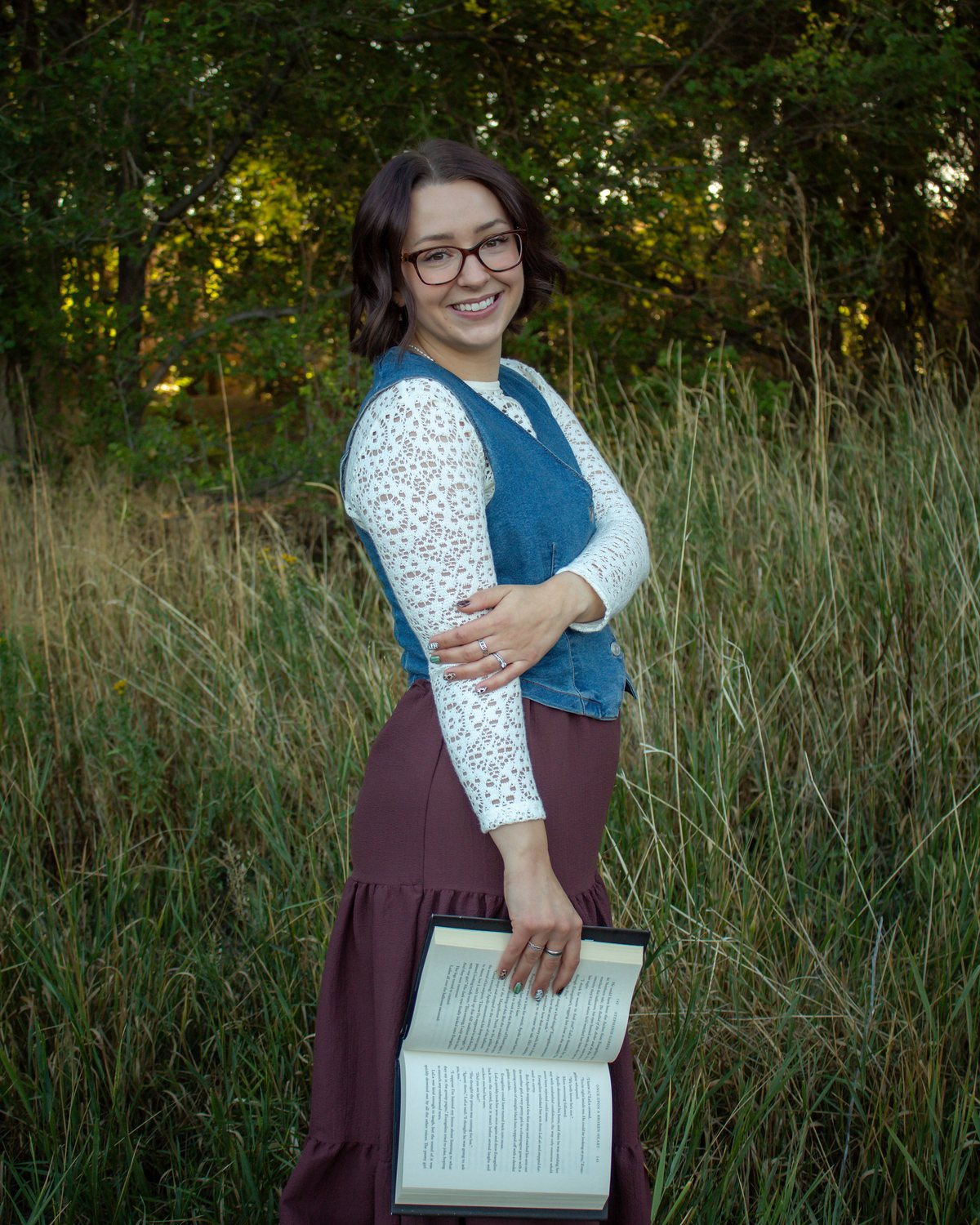 Lynea Millward standing in a field, holding an open book